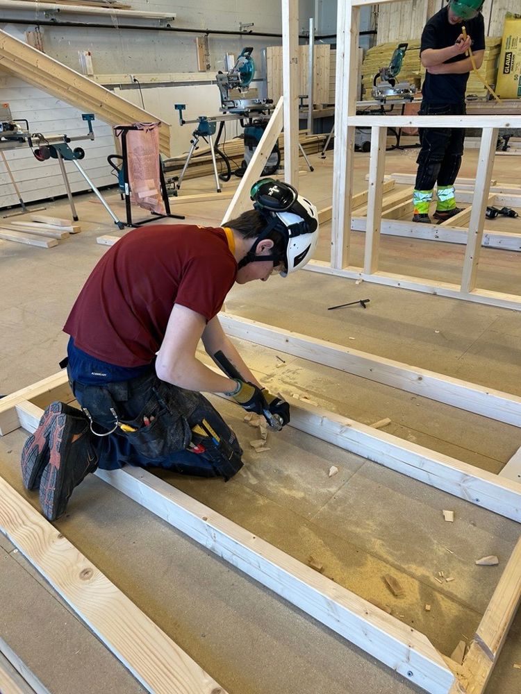 en person med hjelm som jobber på et stykke tre